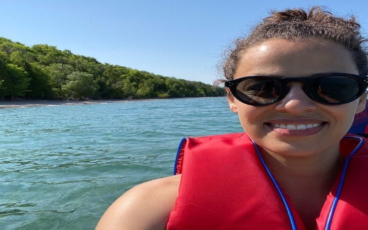 Athena Karkanis in a red life jacket and black sunglasses on a lake.